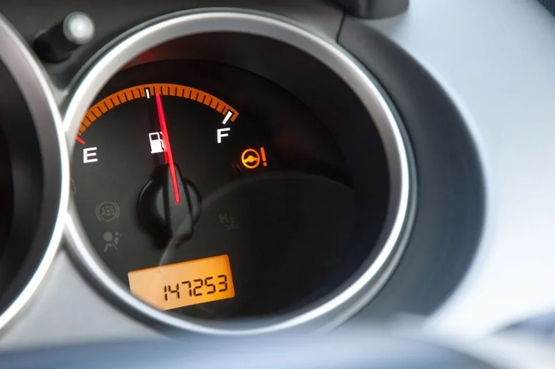 Close-up of a car fuel gauge with the needle at around half a tank, above an odometer reading.
